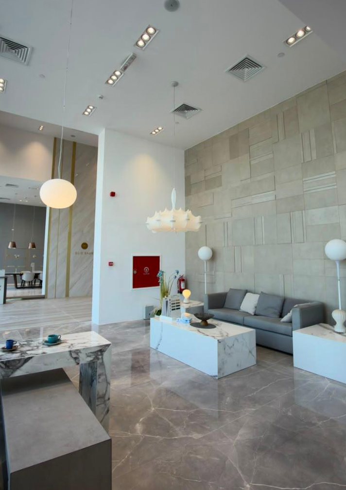 A finished lobby with marble floors, stone feature wall and pendant lighting